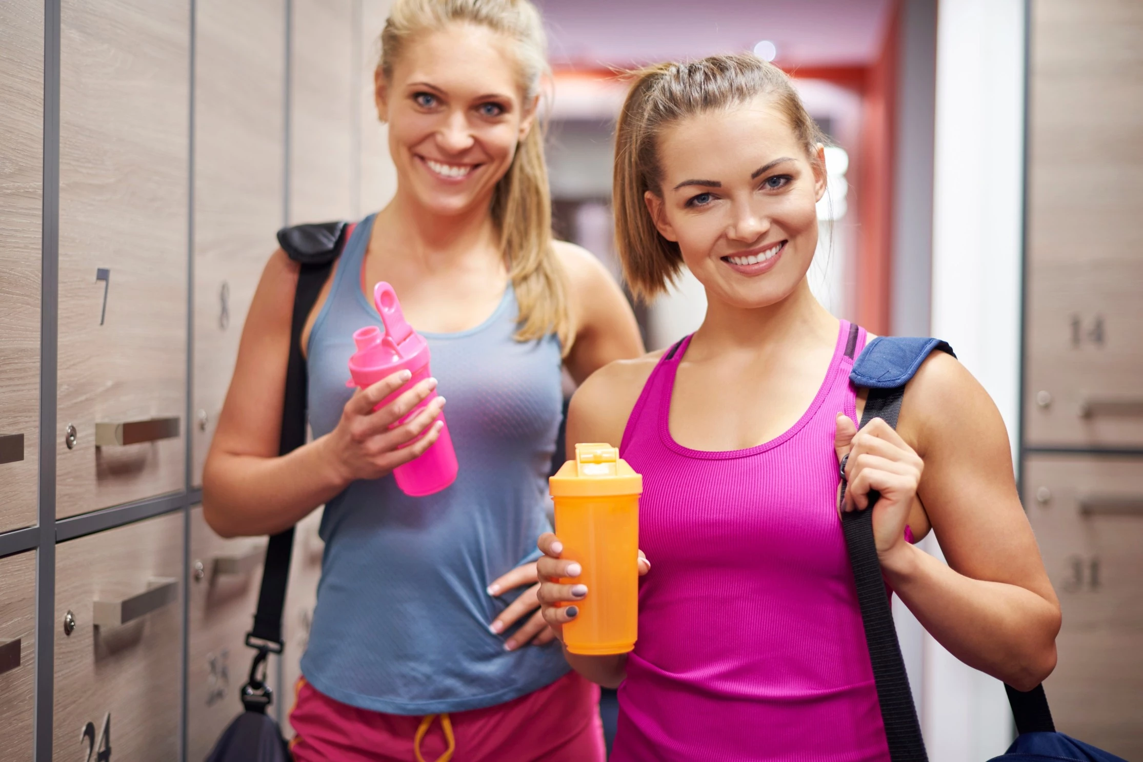 two sports women in the gym having whey protein powder
